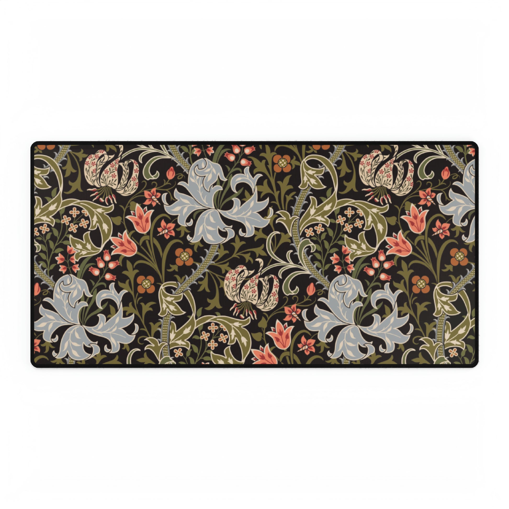 A rectangular desk mat with a William Morris & Co floral pattern in multiple colours, placed under a desk with a keyboard and mouse on top.