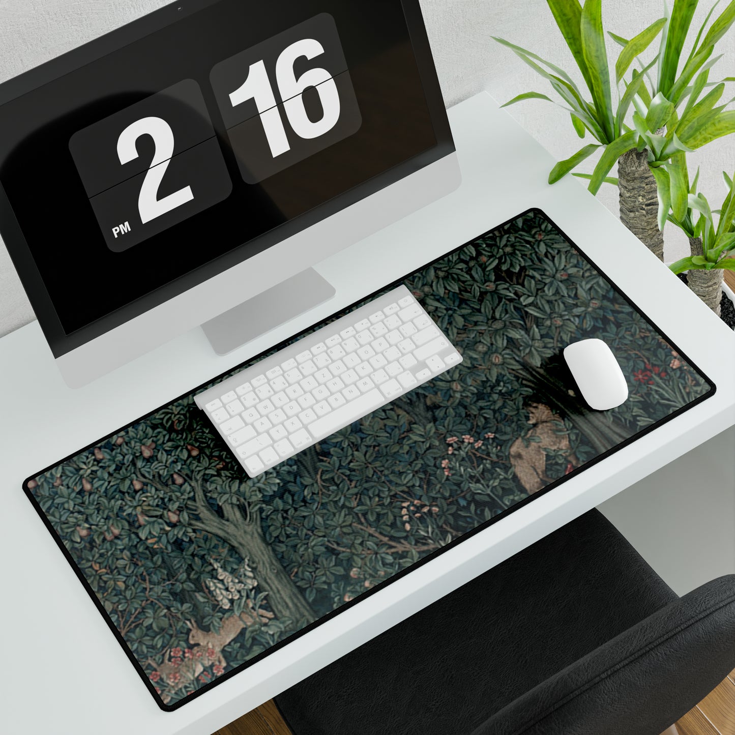 A desk mat with a floral and animal pattern, primarily in green and red colours, featuring a mouse pad on top. The desk mat has a non-slip base and is displayed in a room setting with a monitor, keyboard, and mouse.