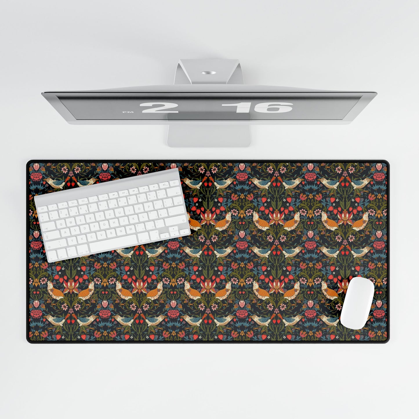 A large, rectangular desk mat with a floral pattern featuring birds and flowers, displayed on a desk with a keyboard and mouse.
