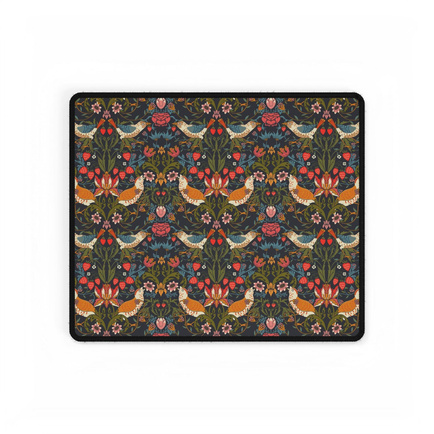 A large, rectangular desk mat with a floral pattern featuring birds and flowers, displayed on a desk with a keyboard and mouse.
