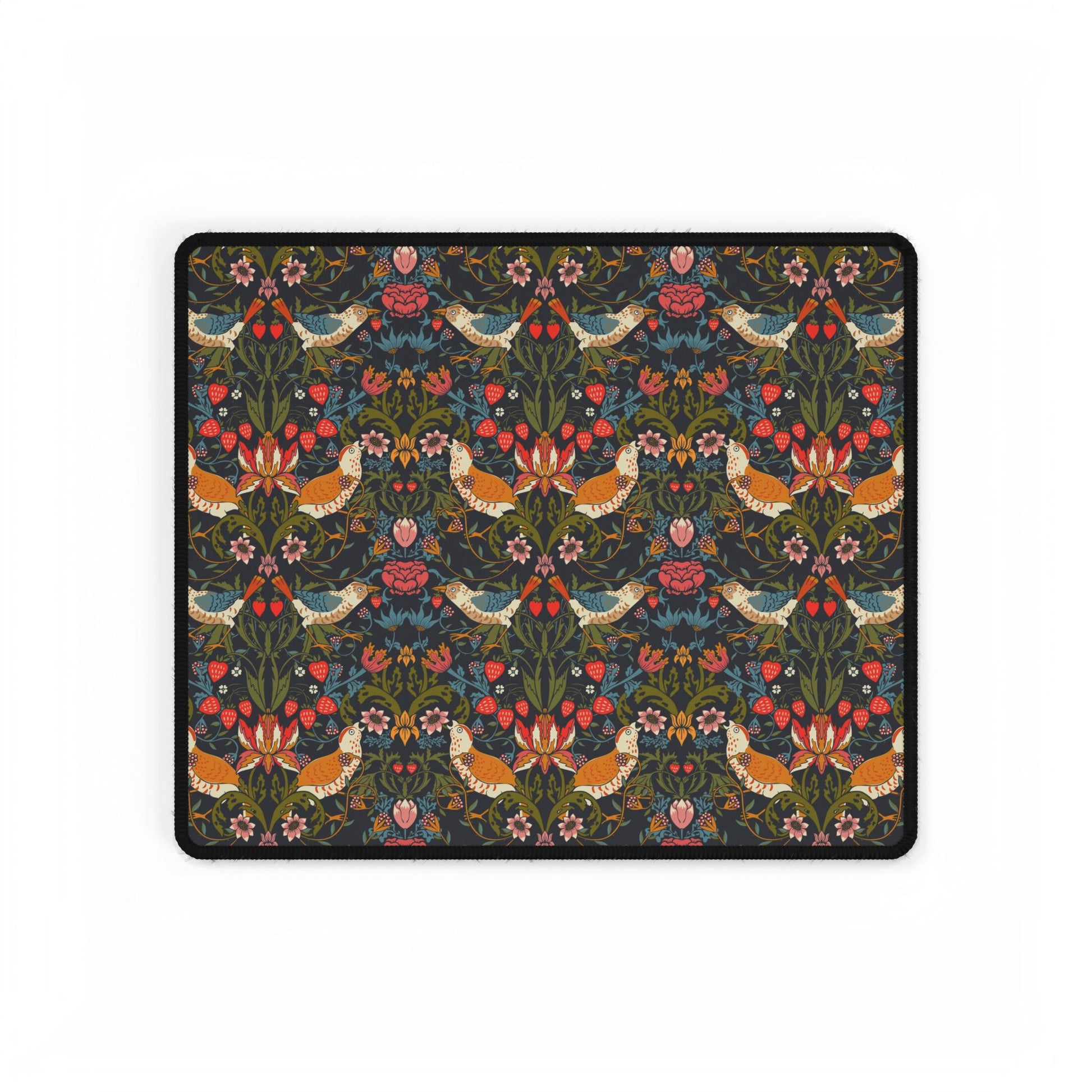 A large, rectangular desk mat with a floral pattern featuring birds and flowers, displayed on a desk with a keyboard and mouse.