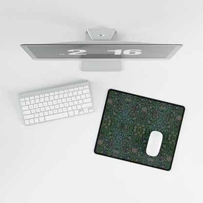 A large desk mat with a floral pattern in green shades, displayed on a desk with a keyboard and mouse.
