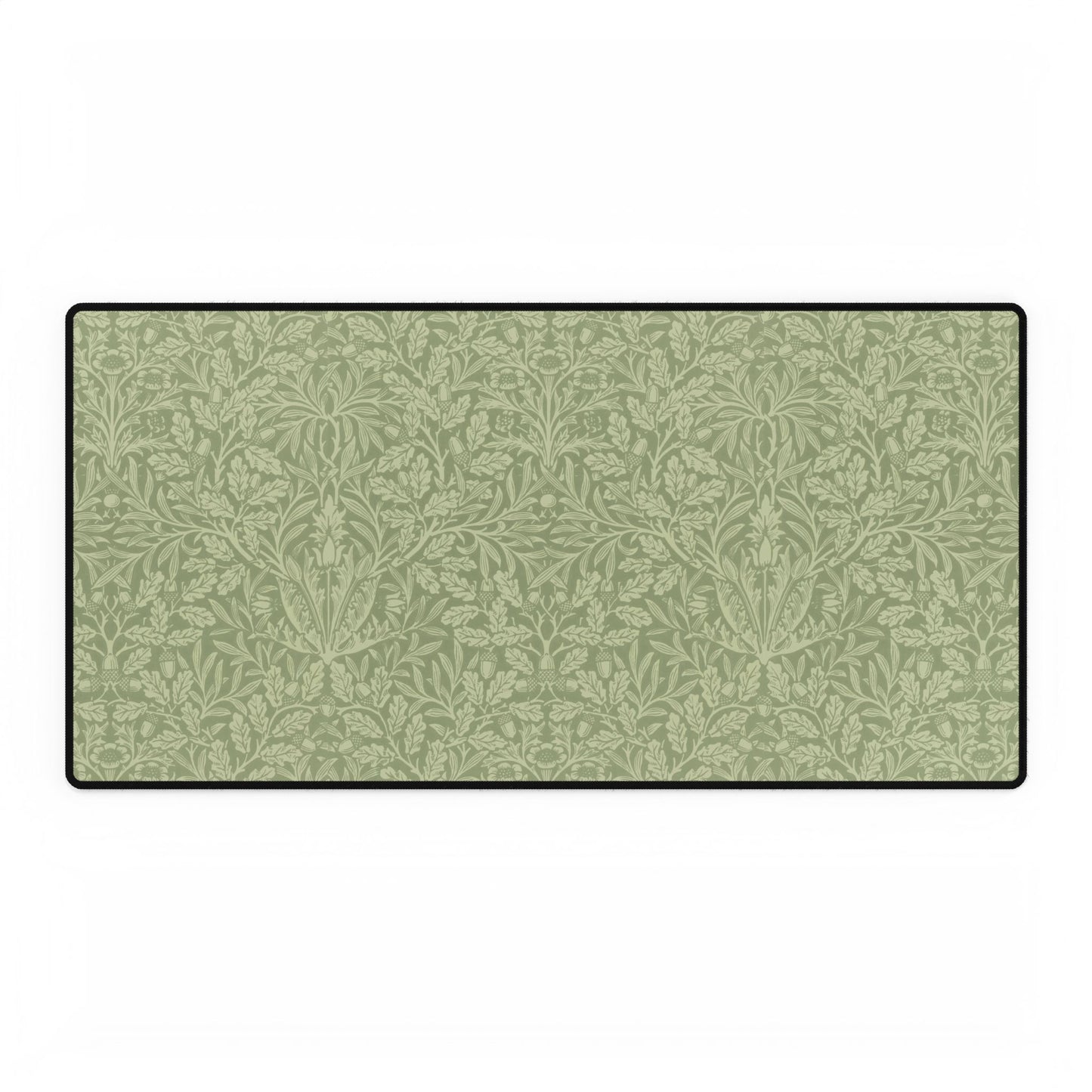 A rectangular desk mat with a green floral pattern, featuring a William Morris & Co oak leaf design, placed under a white desk lamp and a computer mouse on top of the mat.