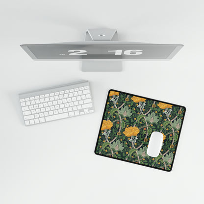 A rectangular desk mat with a floral pattern, specifically featuring chrysanthemums, placed on a desk next to a computer monitor, keyboard, and mouse pad.