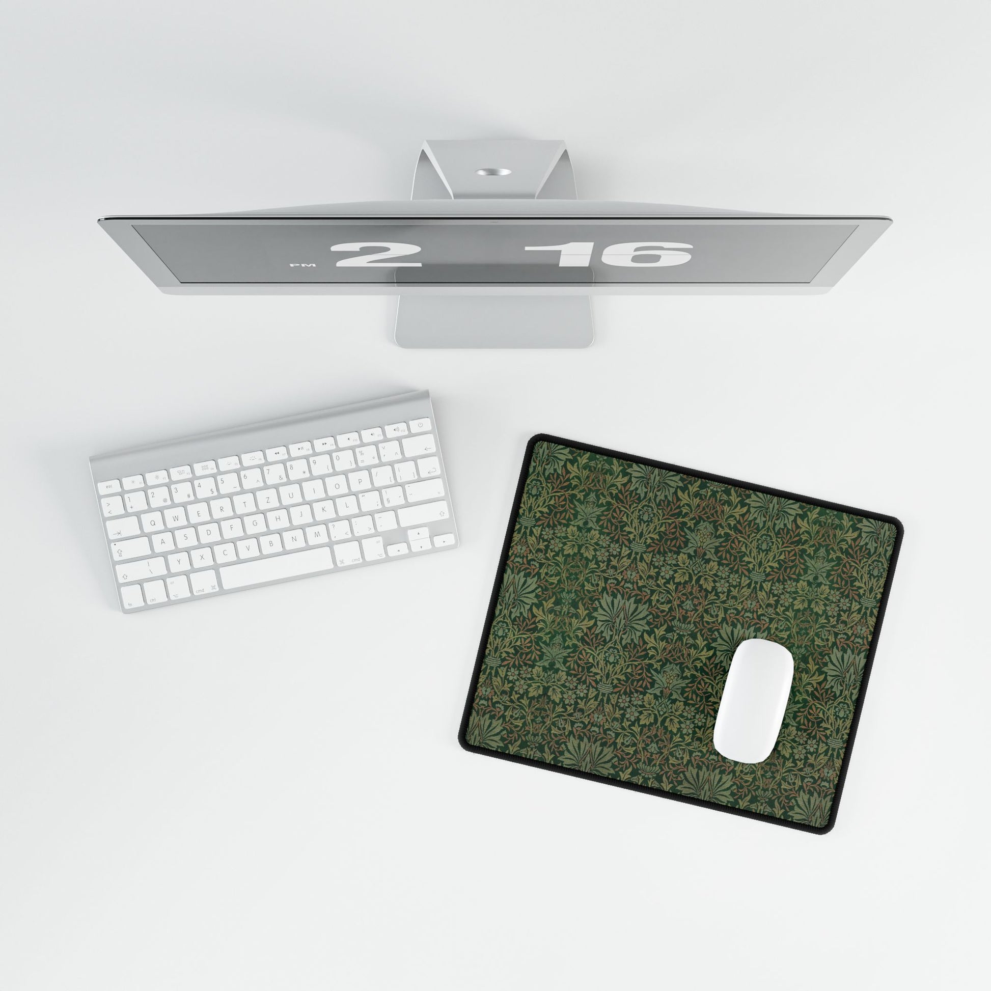 A rectangular desk mat with a floral garden pattern, placed under a desk with a keyboard and mouse on top.