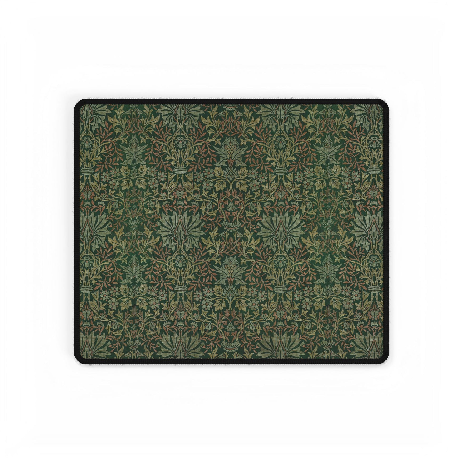 A rectangular desk mat with a floral garden pattern, placed under a desk with a keyboard and mouse on top.