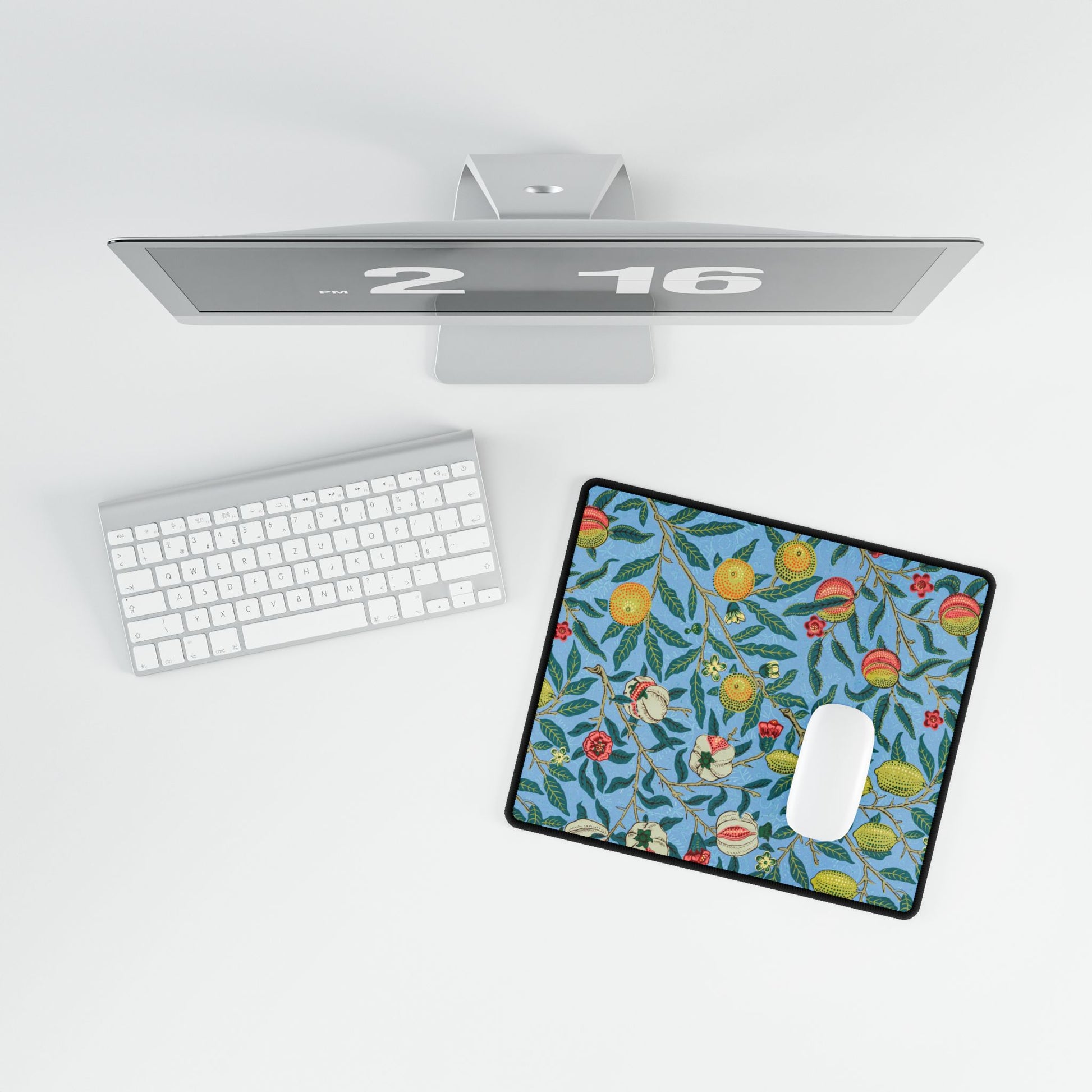 A desk mat with a floral pattern featuring various fruits, placed under a desk with a keyboard and mouse on top.