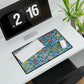 A desk mat with a floral pattern featuring various fruits, placed under a desk with a keyboard and mouse on top.