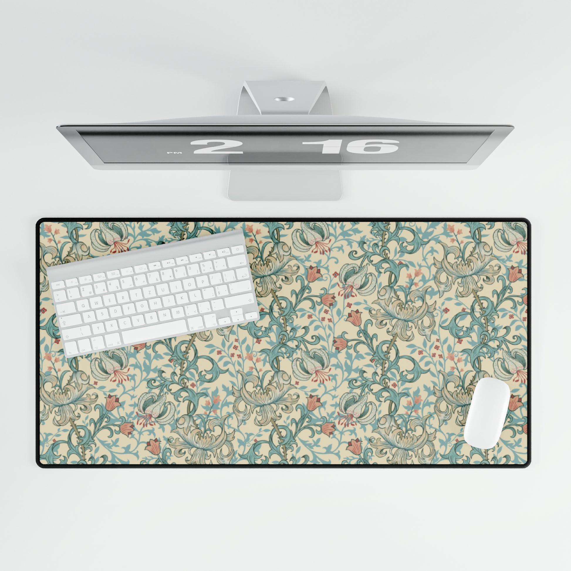 A desk mat with a floral pattern, inspired by William Morris, displayed under a desk with a keyboard and mouse on top.