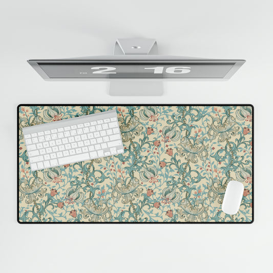 A desk mat with a floral pattern, inspired by William Morris, displayed under a desk with a keyboard and mouse on top.