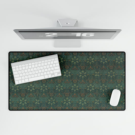 A rectangular desk mat with a William Morris & Co floral pattern in green, brown, and white, placed under a white desk and a keyboard.