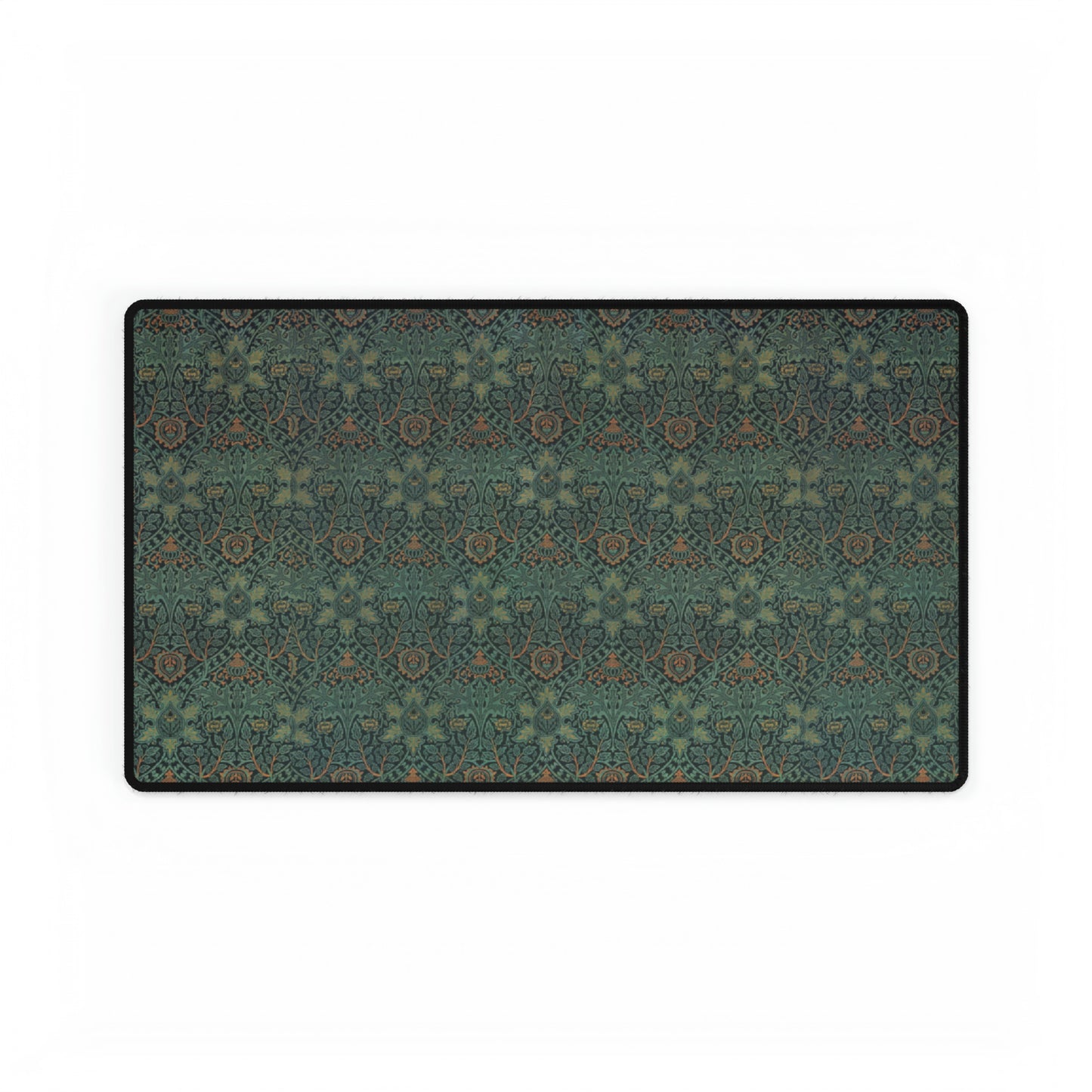 A rectangular desk mat with a William Morris & Co floral pattern in green, brown, and white, placed under a white desk and a keyboard.