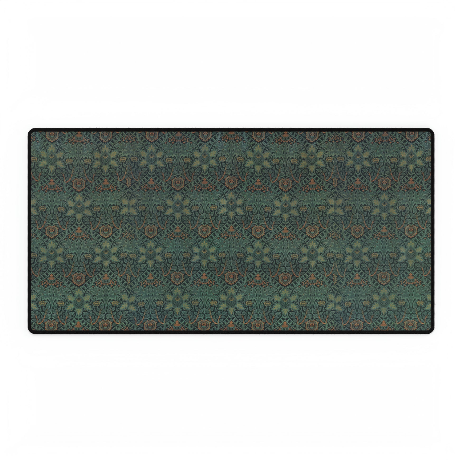 A rectangular desk mat with a William Morris & Co floral pattern in green, brown, and white, placed under a white desk and a keyboard.