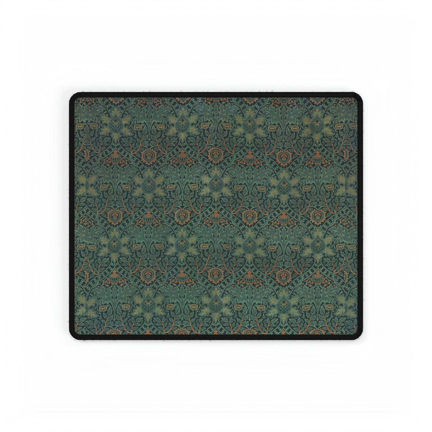 A rectangular desk mat with a William Morris & Co floral pattern in green, brown, and white, placed under a white desk and a keyboard.