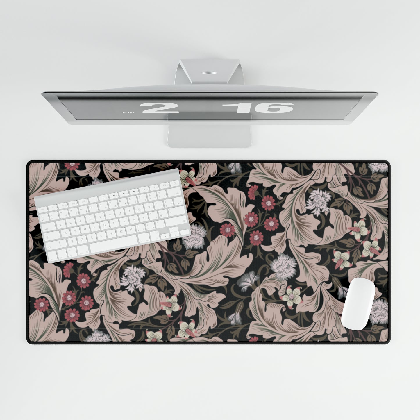 A large desk mat with a William Morris & Co floral pattern in mocha and black colours, displayed on a desk with a keyboard and mouse.