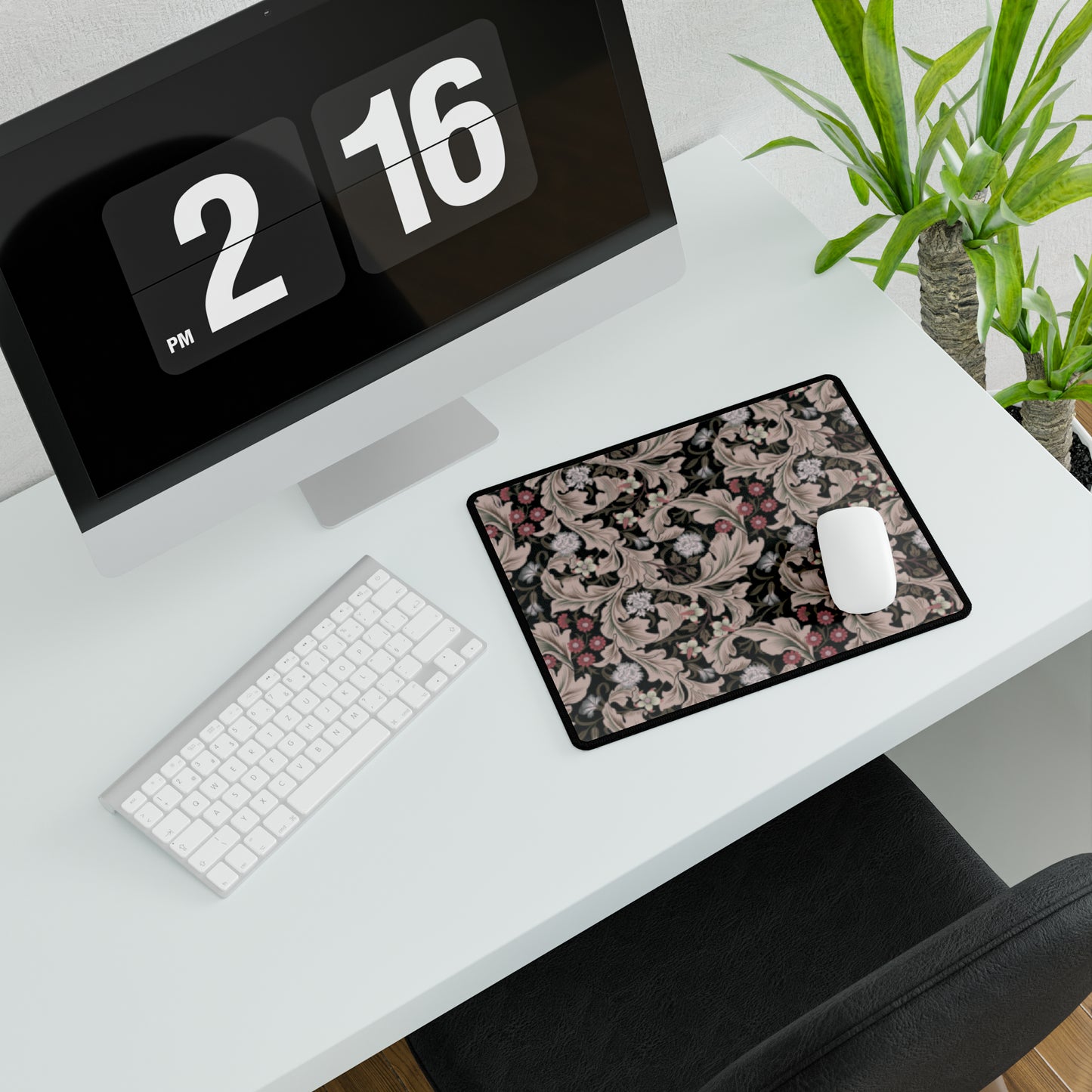 A large desk mat with a William Morris & Co floral pattern in mocha and black colours, displayed on a desk with a keyboard and mouse.