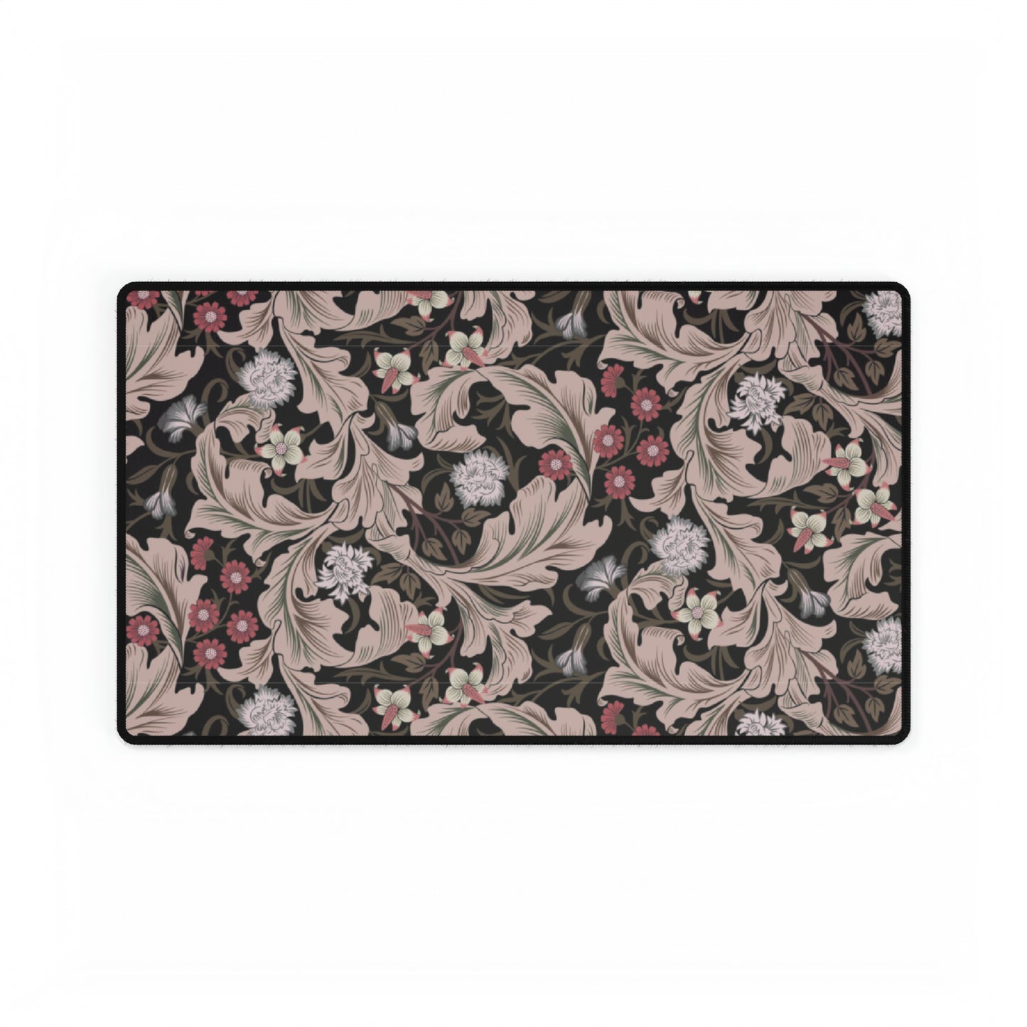 A large desk mat with a William Morris & Co floral pattern in mocha and black colours, displayed on a desk with a keyboard and mouse.