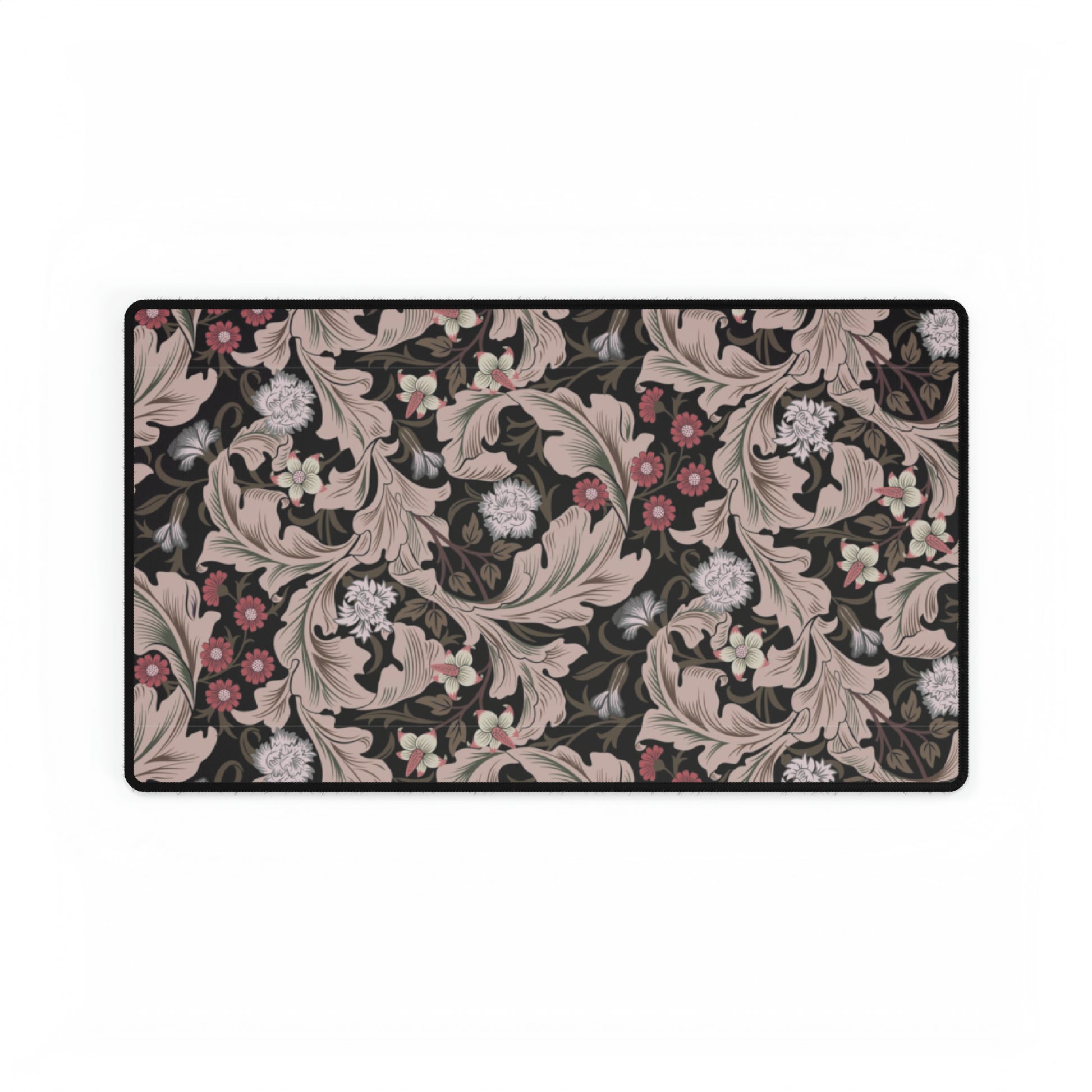 A large desk mat with a William Morris & Co floral pattern in mocha and black colours, displayed on a desk with a keyboard and mouse.