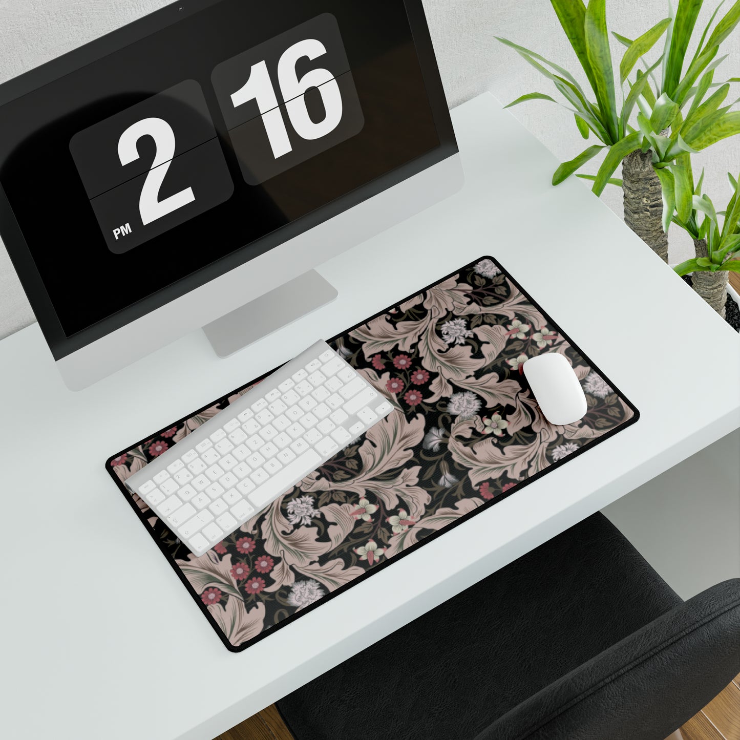 A large desk mat with a William Morris & Co floral pattern in mocha and black colours, displayed on a desk with a keyboard and mouse.
