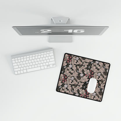 A large desk mat with a floral pattern in mocha and black colors, displayed on a desk with a keyboard and mouse.