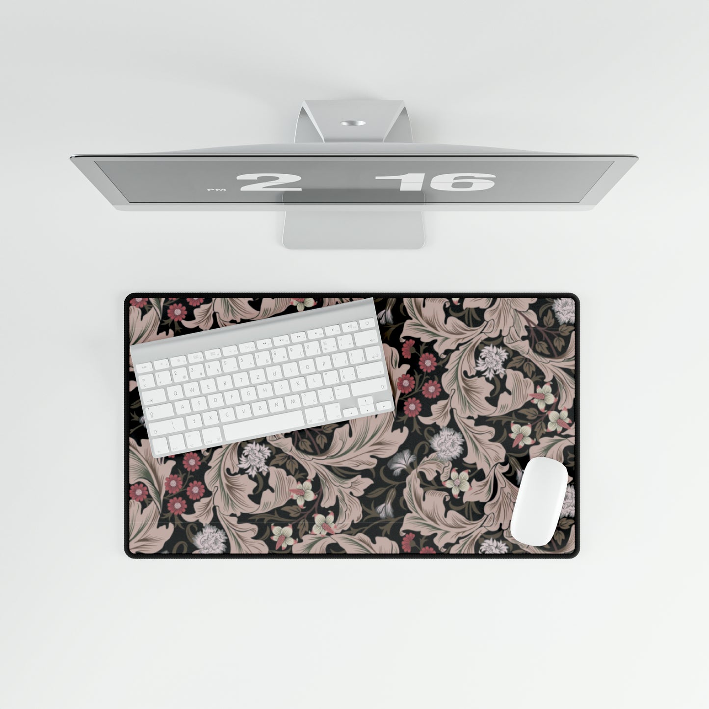 A large desk mat with a floral pattern in mocha and black colors, displayed on a desk with a keyboard and mouse.