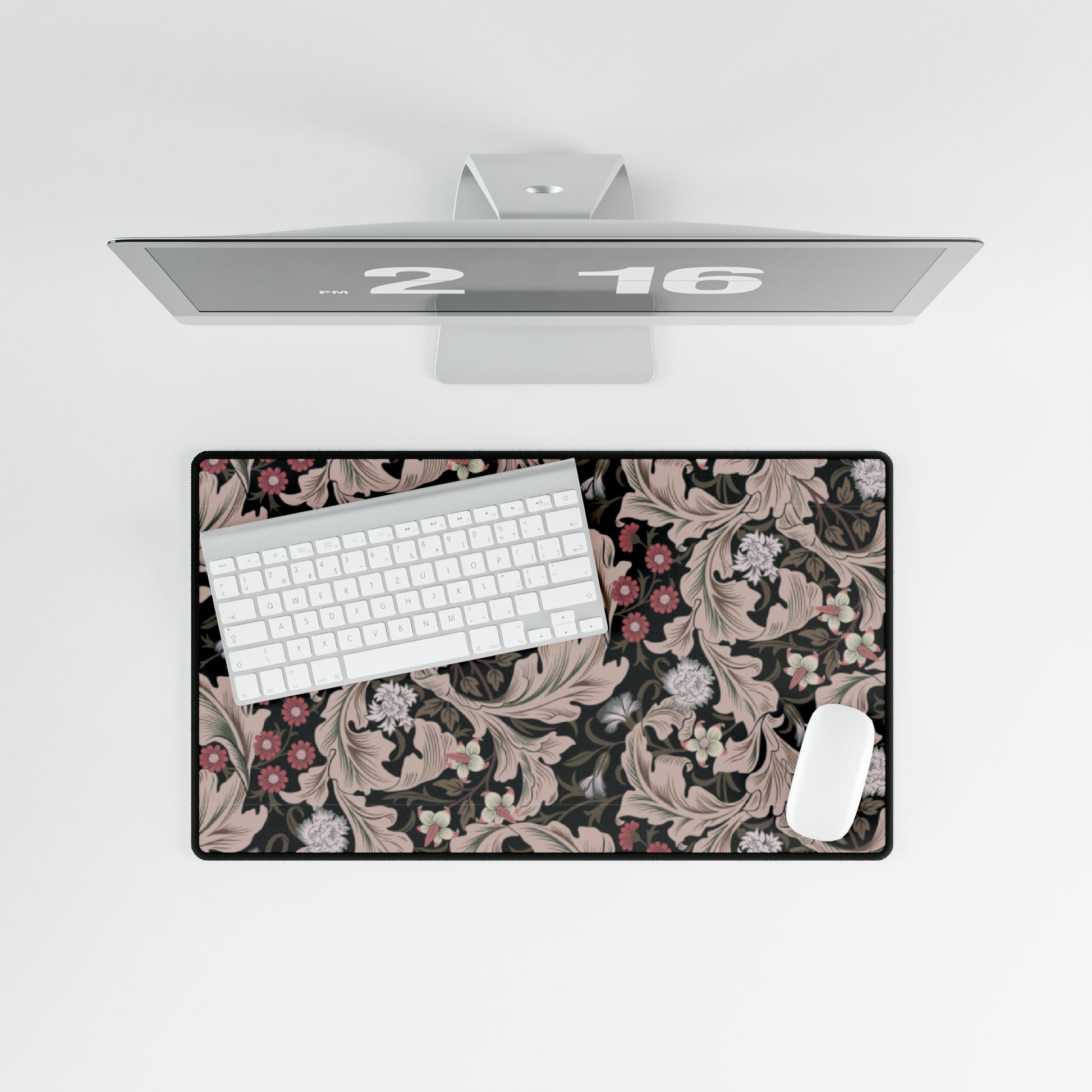 A large desk mat with a floral pattern in mocha and black colors, displayed on a desk with a keyboard and mouse.