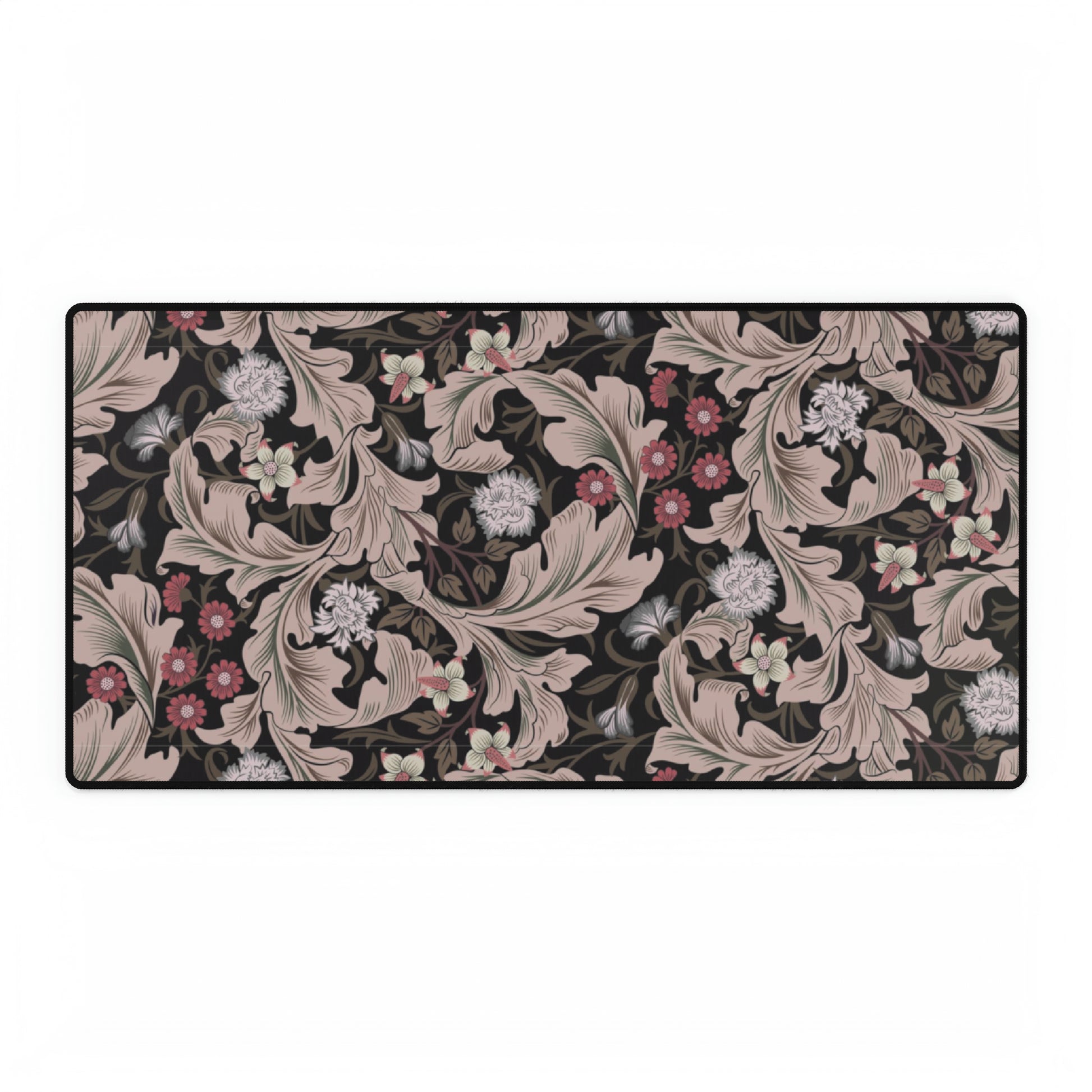 A large desk mat with a William Morris & Co floral pattern in mocha and black colours, displayed on a desk with a keyboard and mouse.