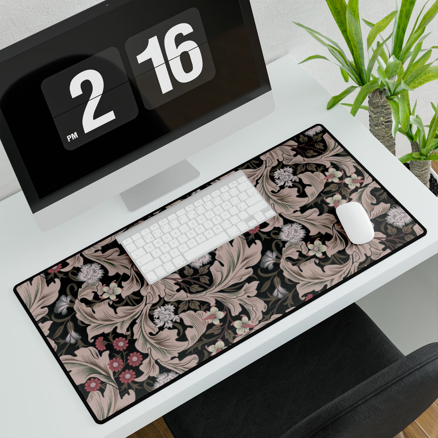 A large desk mat with a William Morris & Co floral pattern in mocha and black colours, displayed on a desk with a keyboard and mouse.