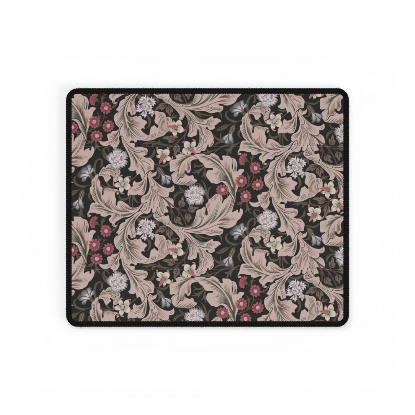 A large desk mat with a William Morris & Co floral pattern in mocha and black colours, displayed on a desk with a keyboard and mouse.