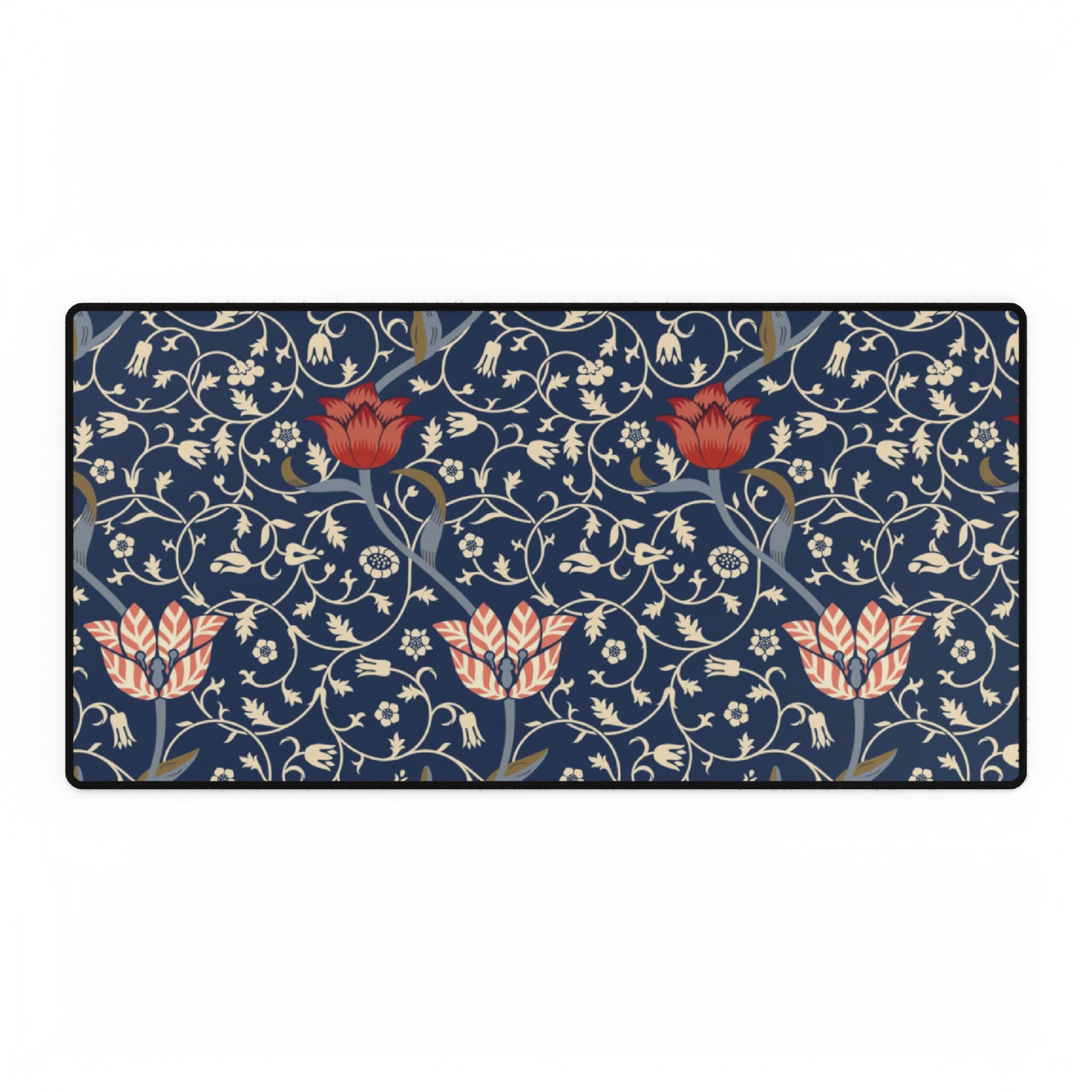 A large desk mat with a floral pattern in shades of red, pink and blue on a dark background, displayed under a monitor with a keyboard and mouse on top.