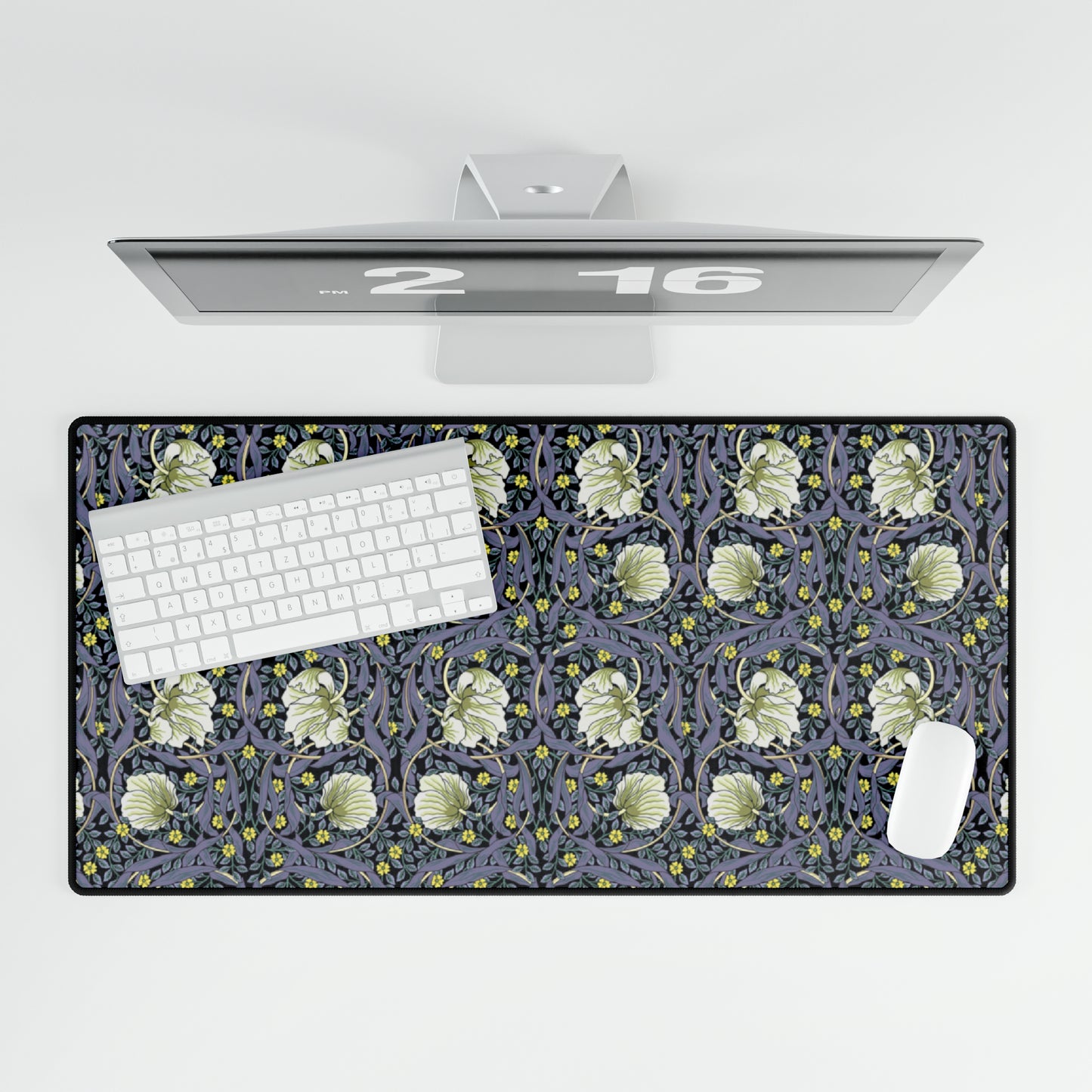 A large desk mat with a William Morris & Co floral pattern in shades of purple and green, displayed on a desk with a keyboard and mouse.