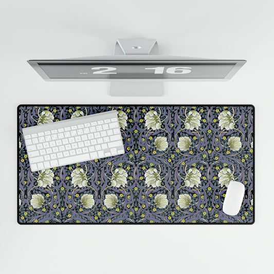 A large desk mat with a William Morris & Co floral pattern in shades of purple and green, displayed on a desk with a keyboard and mouse.