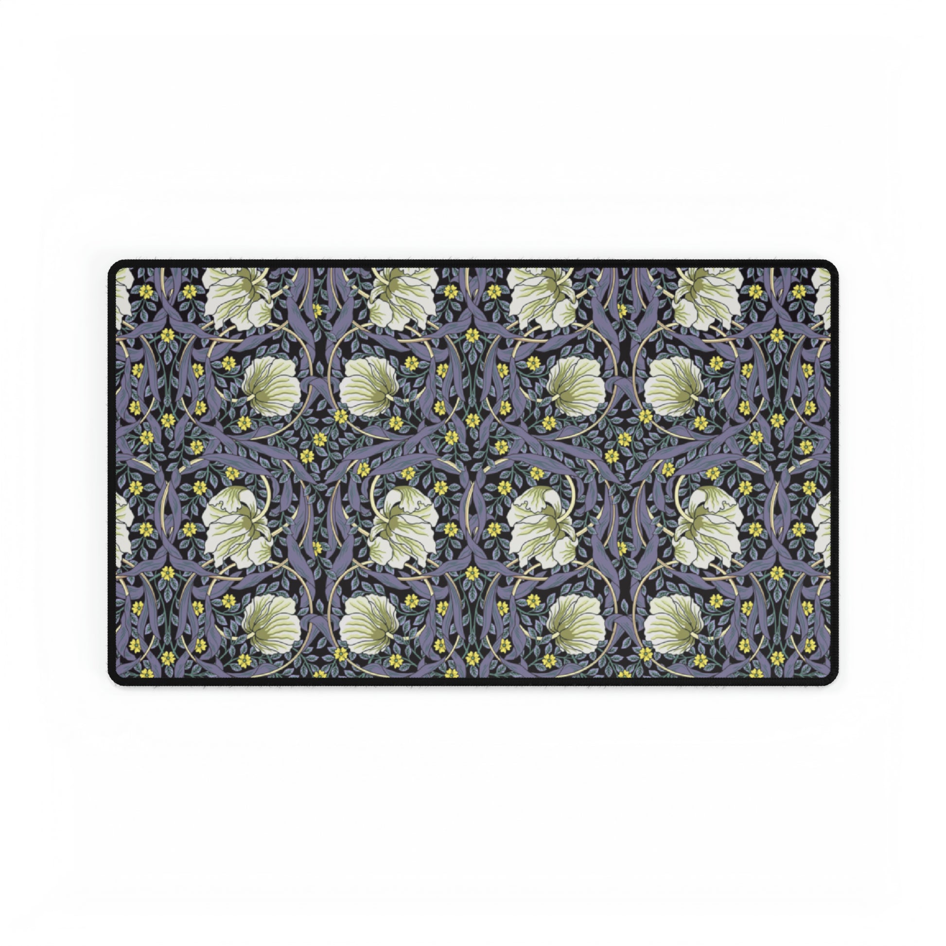 A large desk mat with a William Morris & Co floral pattern in shades of purple and green, displayed on a desk with a keyboard and mouse.