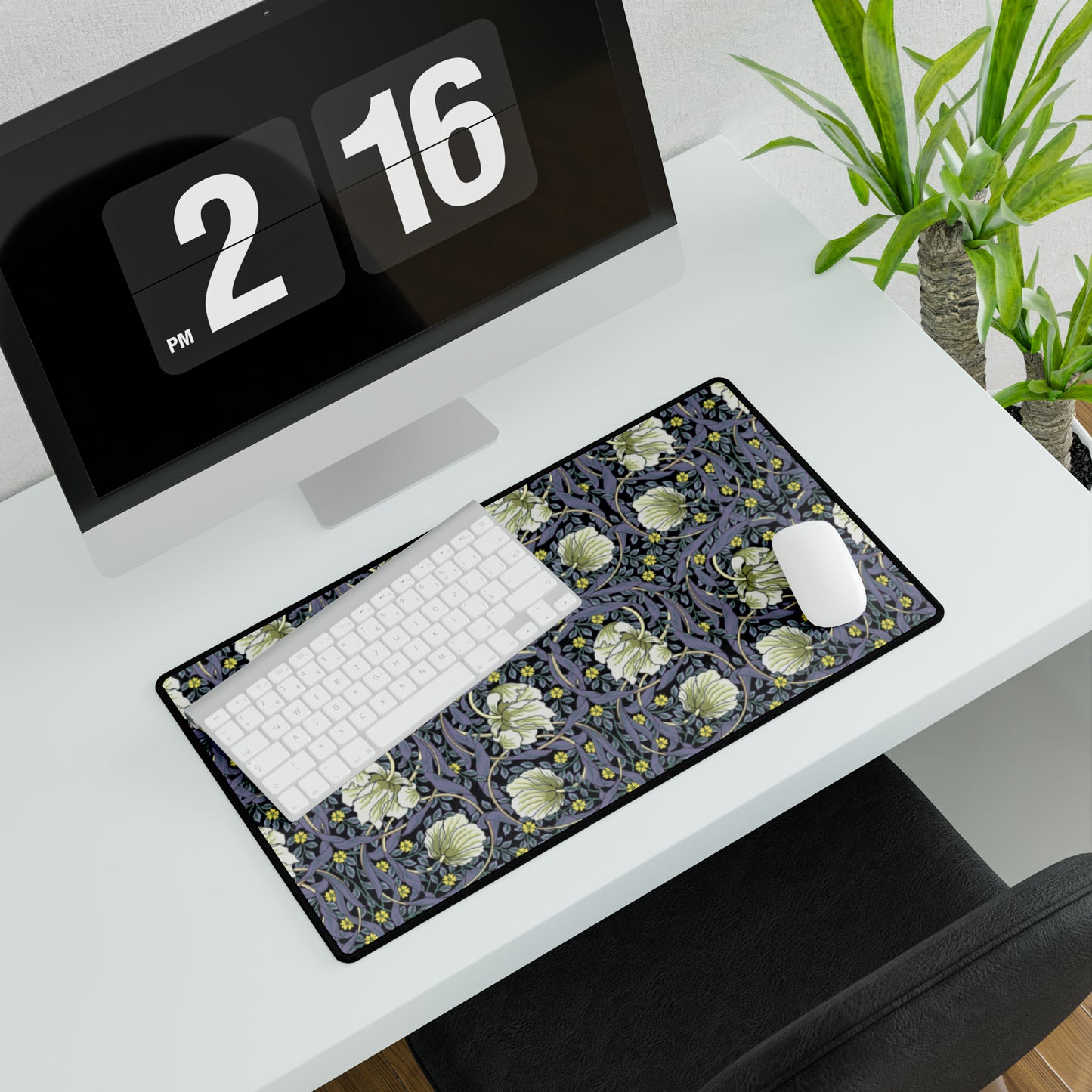 A large desk mat with a William Morris & Co floral pattern in shades of purple and green, displayed on a desk with a keyboard and mouse.