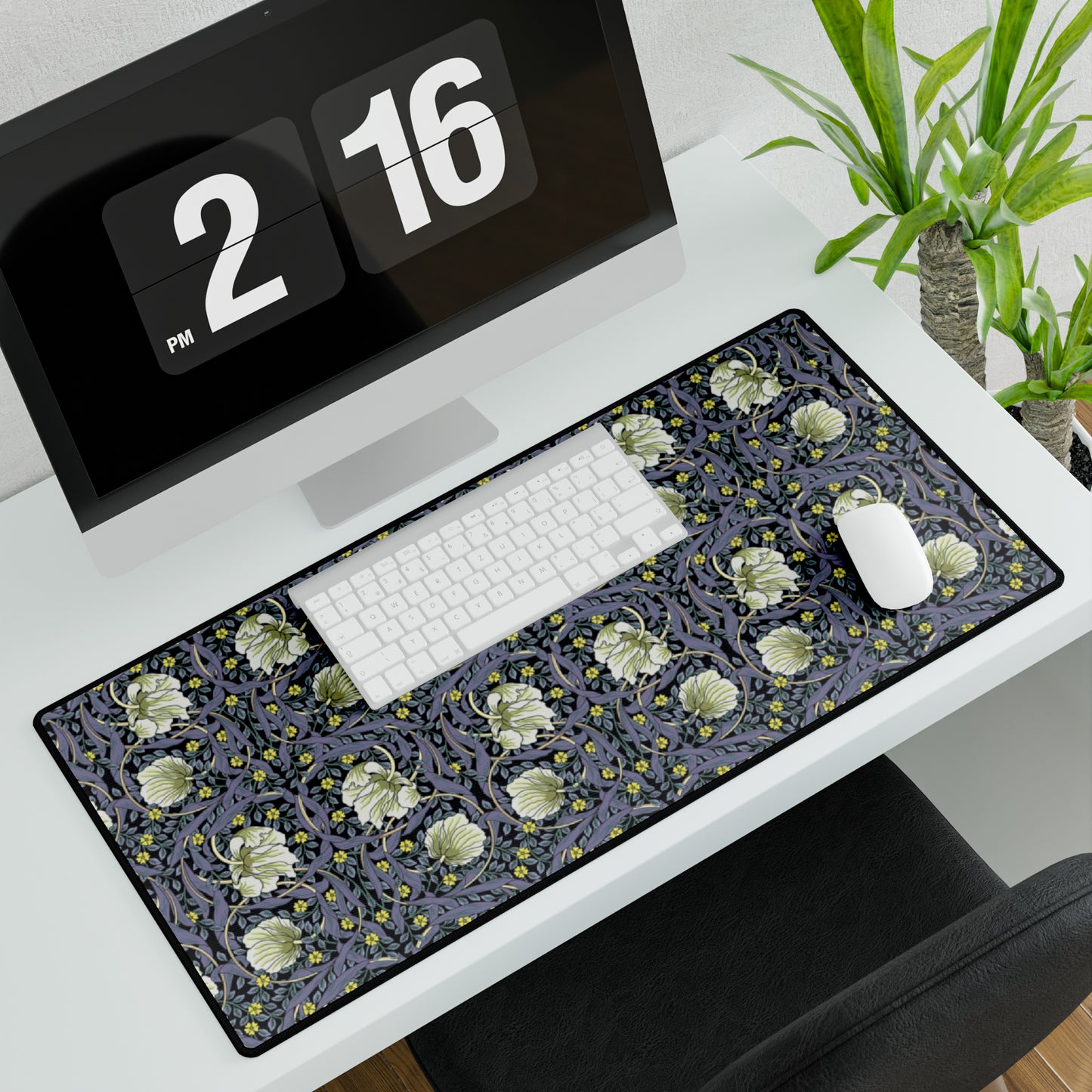 A large desk mat with a William Morris & Co floral pattern in shades of purple and green, displayed on a desk with a keyboard and mouse.