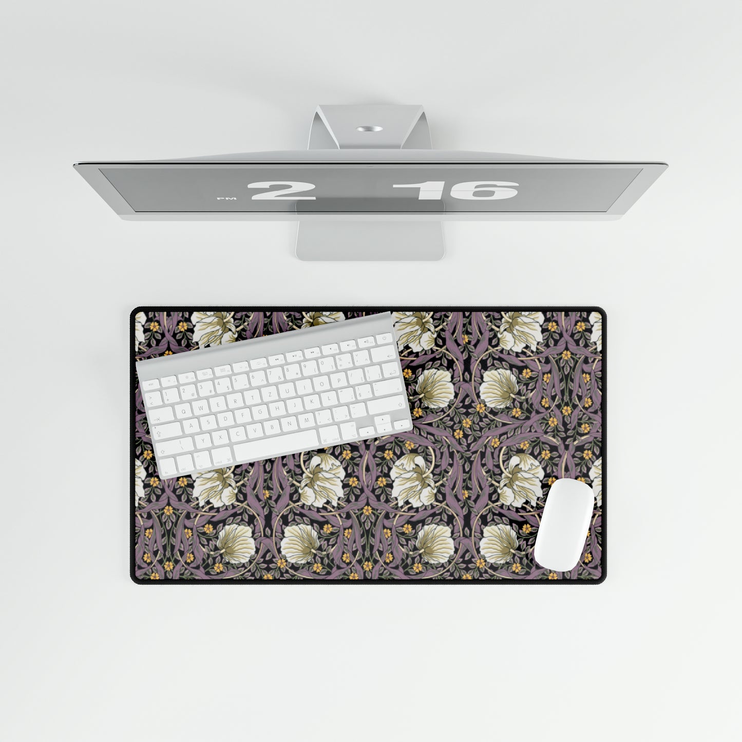 A large desk mat with a floral pattern, displayed on a desk with a keyboard and mouse, with a monitor above it showing a part of the mat.