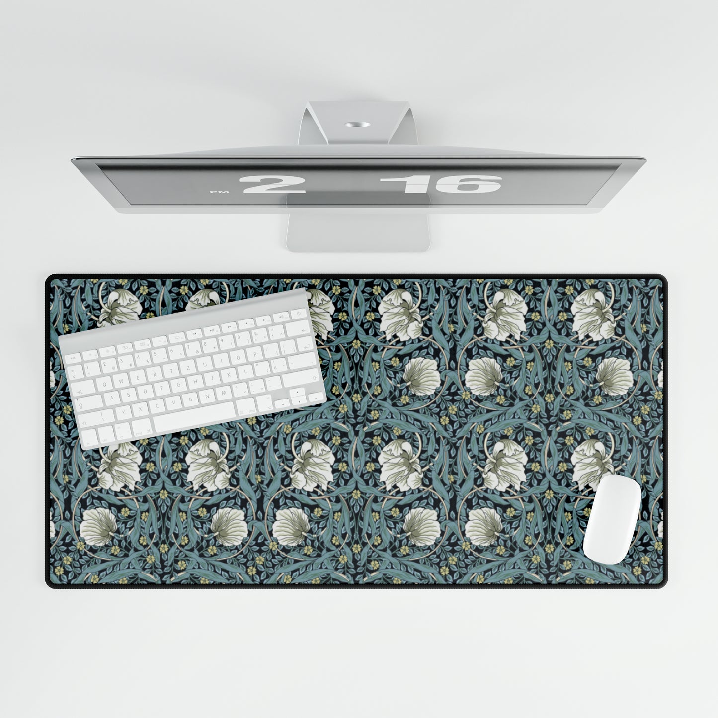 A large desk mat with a William Morris & Co floral pattern in shades of gray and blue, displayed on a desk with a keyboard and mouse.