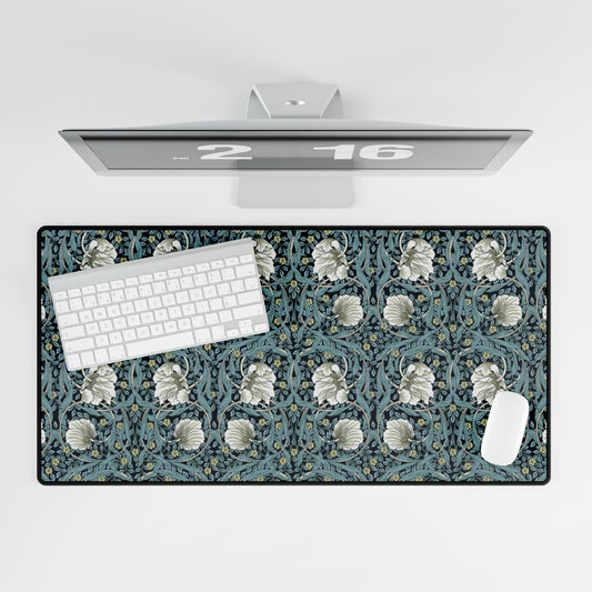 A large desk mat with a William Morris & Co floral pattern in shades of gray and blue, displayed on a desk with a keyboard and mouse.