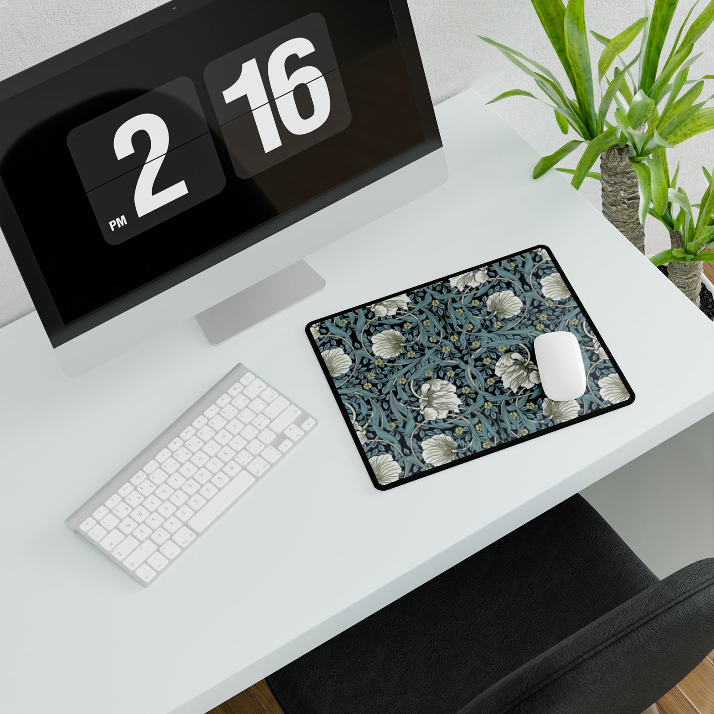 A large desk mat with a William Morris & Co floral pattern in shades of gray and blue, displayed on a desk with a keyboard and mouse.