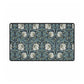 A large desk mat with a William Morris & Co floral pattern in shades of gray and blue, displayed on a desk with a keyboard and mouse.