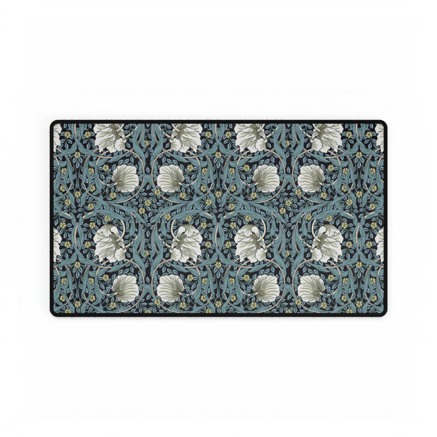 A large desk mat with a William Morris & Co floral pattern in shades of gray and blue, displayed on a desk with a keyboard and mouse.