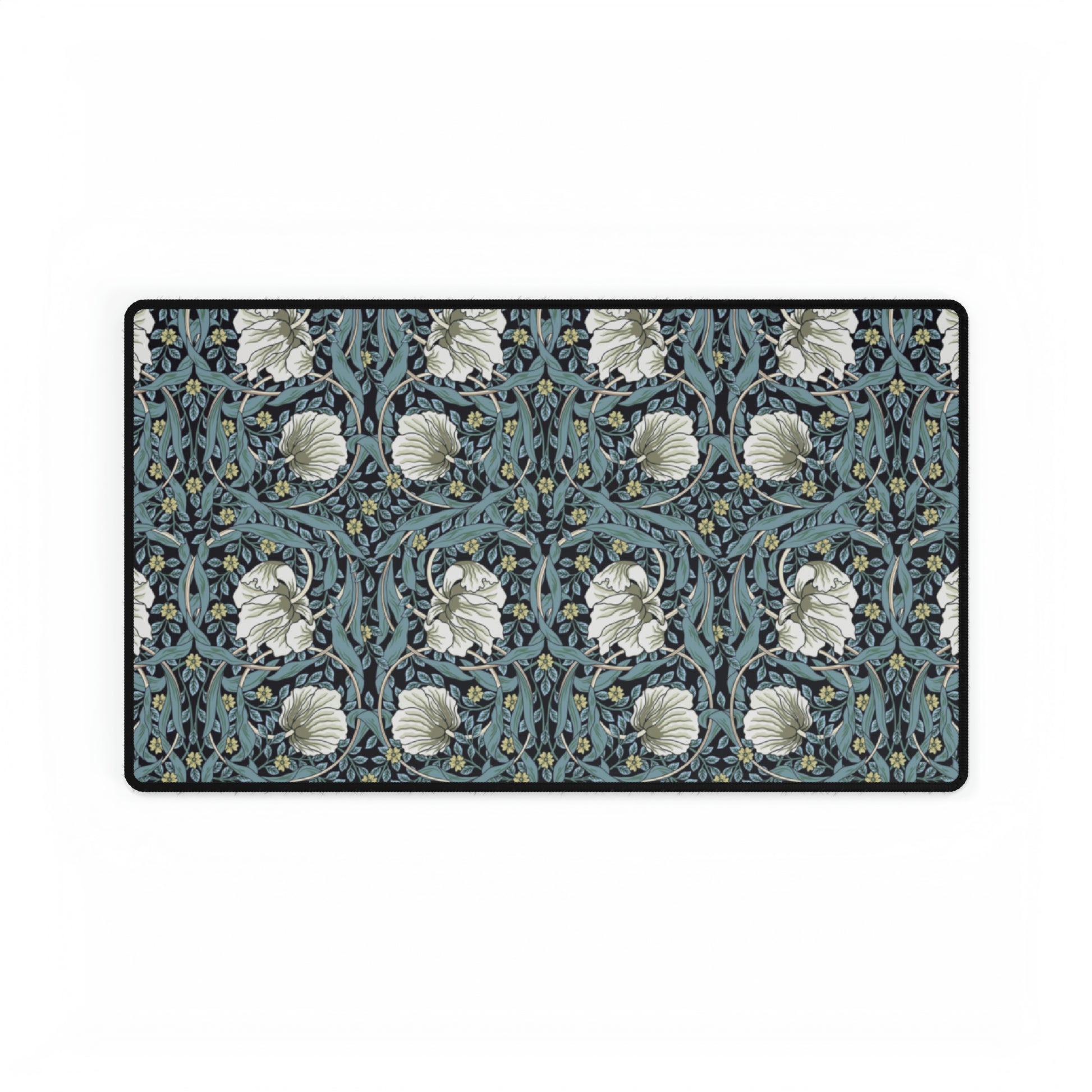 A large desk mat with a William Morris & Co floral pattern in shades of gray and blue, displayed on a desk with a keyboard and mouse.