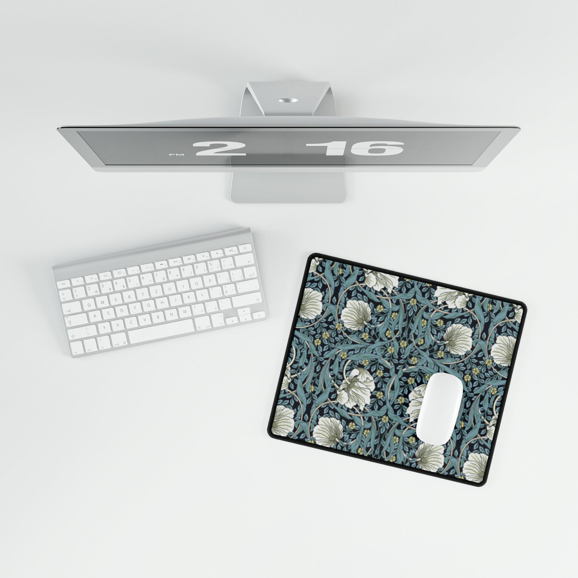 A large desk mat with a William Morris & Co floral pattern in shades of gray and blue, displayed on a desk with a keyboard and mouse.