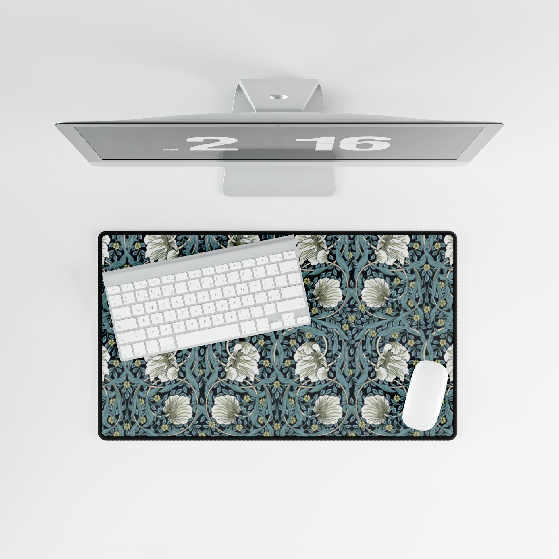 A large desk mat with a William Morris & Co floral pattern in shades of gray and blue, displayed on a desk with a keyboard and mouse.