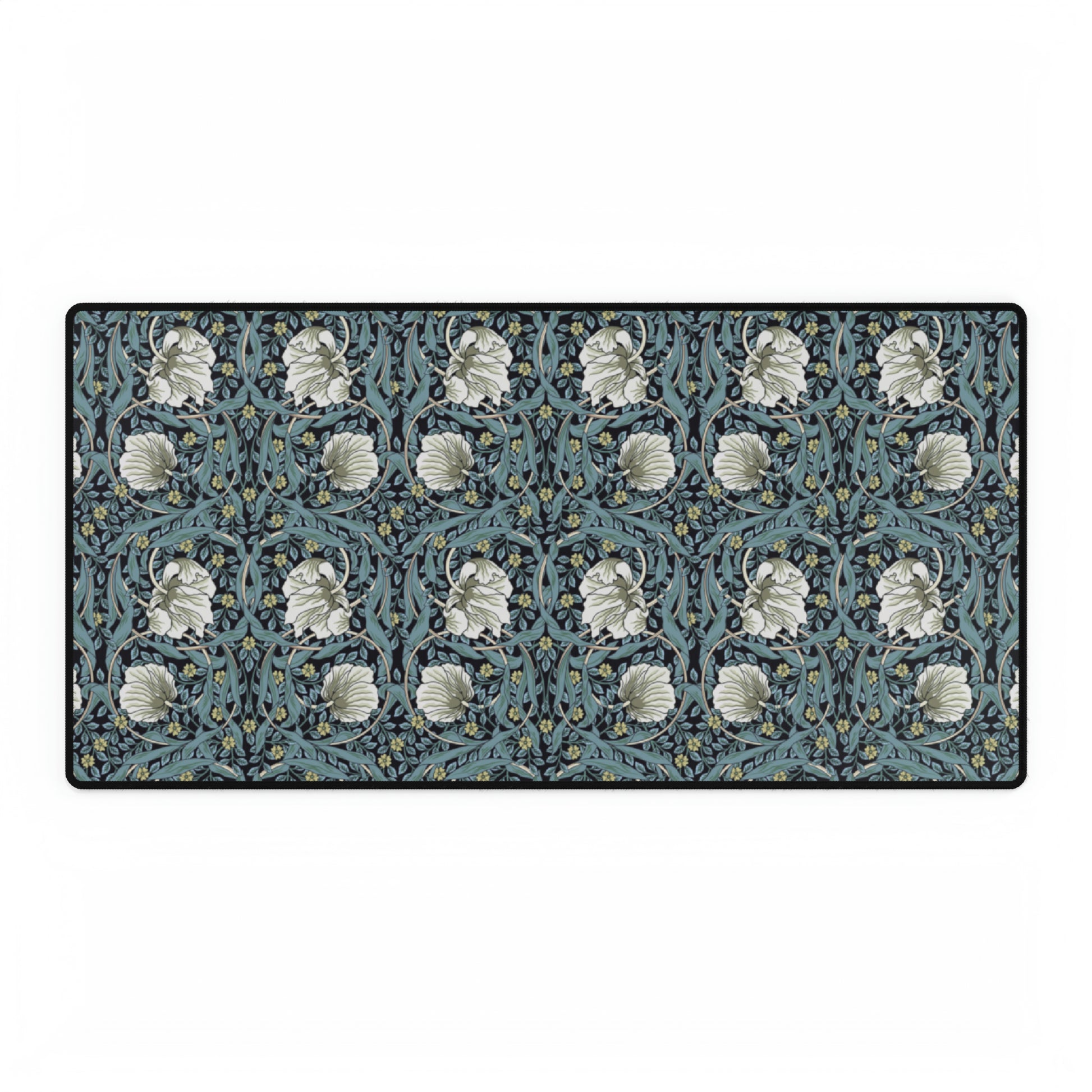 A large desk mat with a William Morris & Co floral pattern in shades of gray and blue, displayed on a desk with a keyboard and mouse.