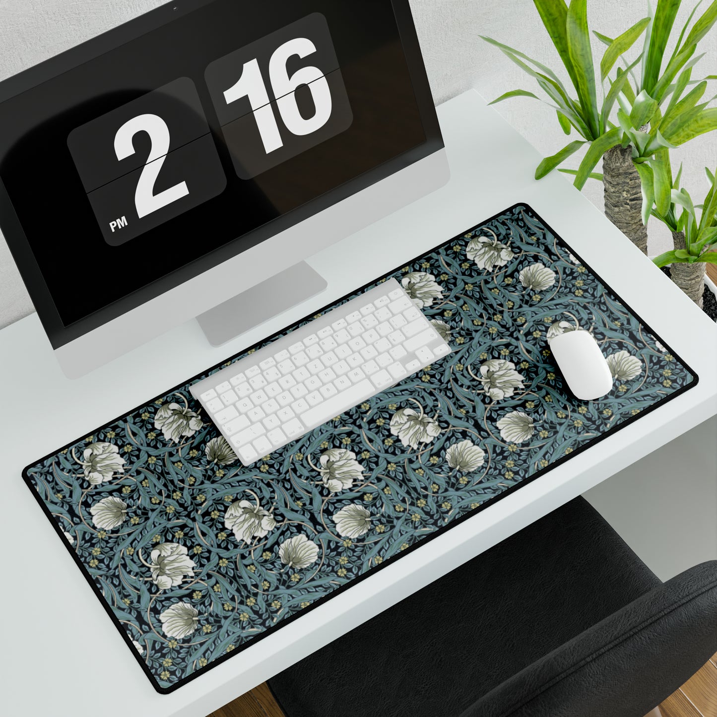 A large desk mat with a William Morris & Co floral pattern in shades of gray and blue, displayed on a desk with a keyboard and mouse.