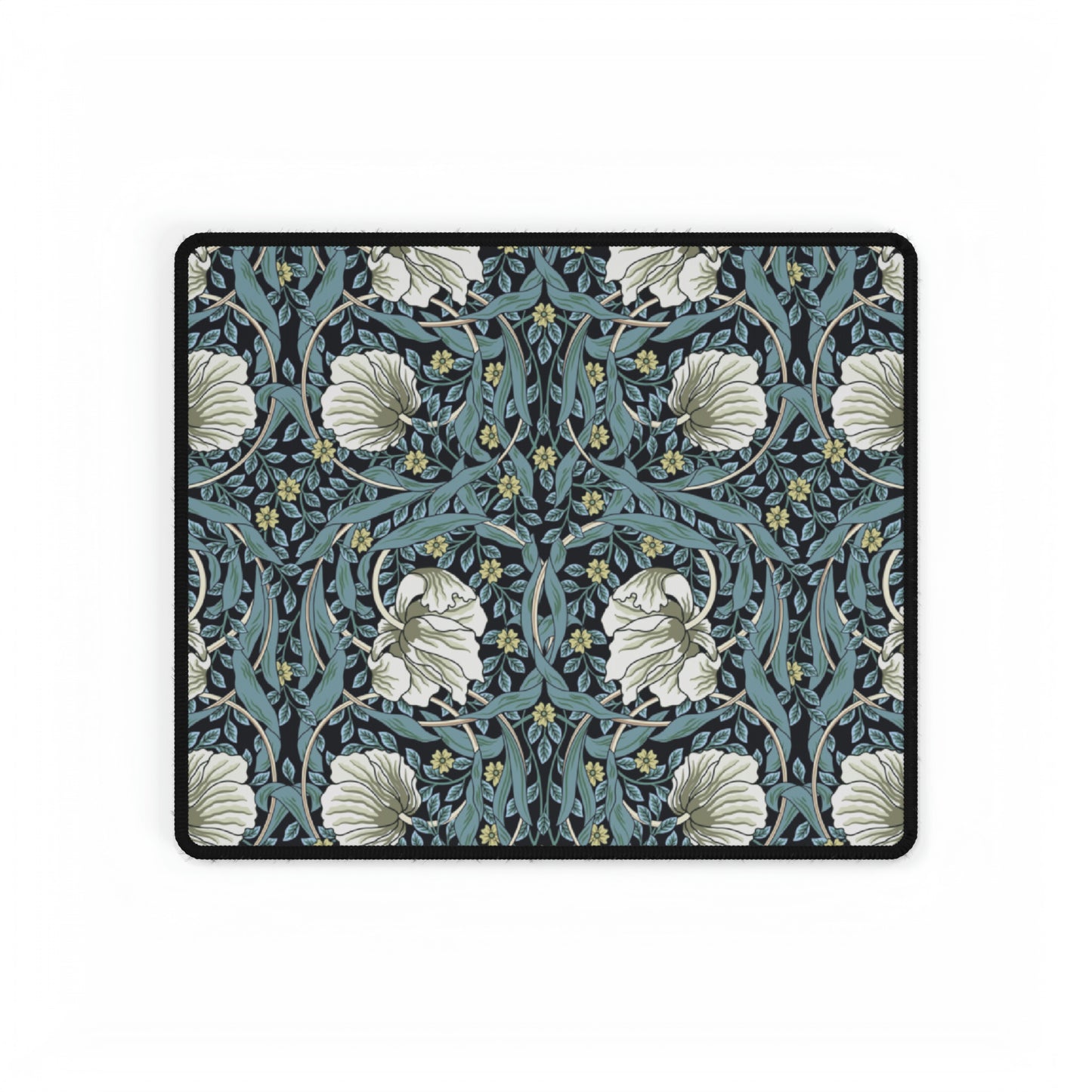 A large desk mat with a William Morris & Co floral pattern in shades of gray and blue, displayed on a desk with a keyboard and mouse.