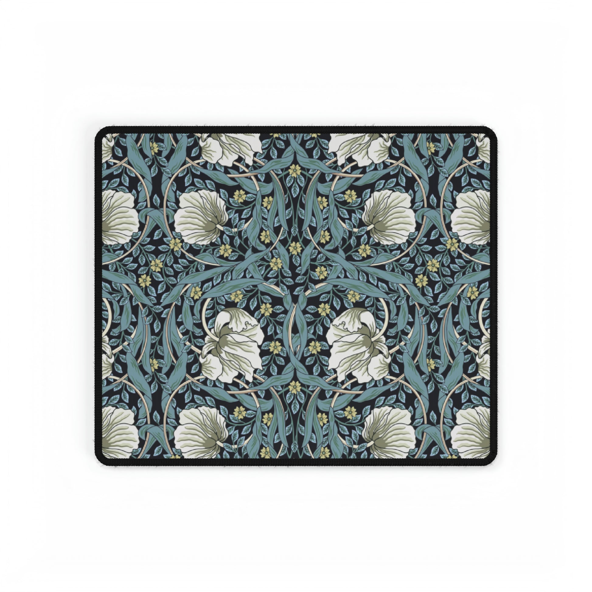 A large desk mat with a William Morris & Co floral pattern in shades of gray and blue, displayed on a desk with a keyboard and mouse.