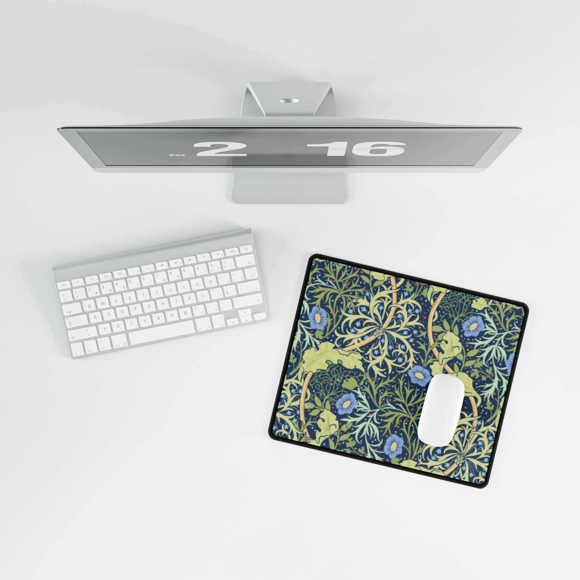 A large desk mat with a blue floral pattern displayed under a monitor and accompanied by a keyboard and mouse.