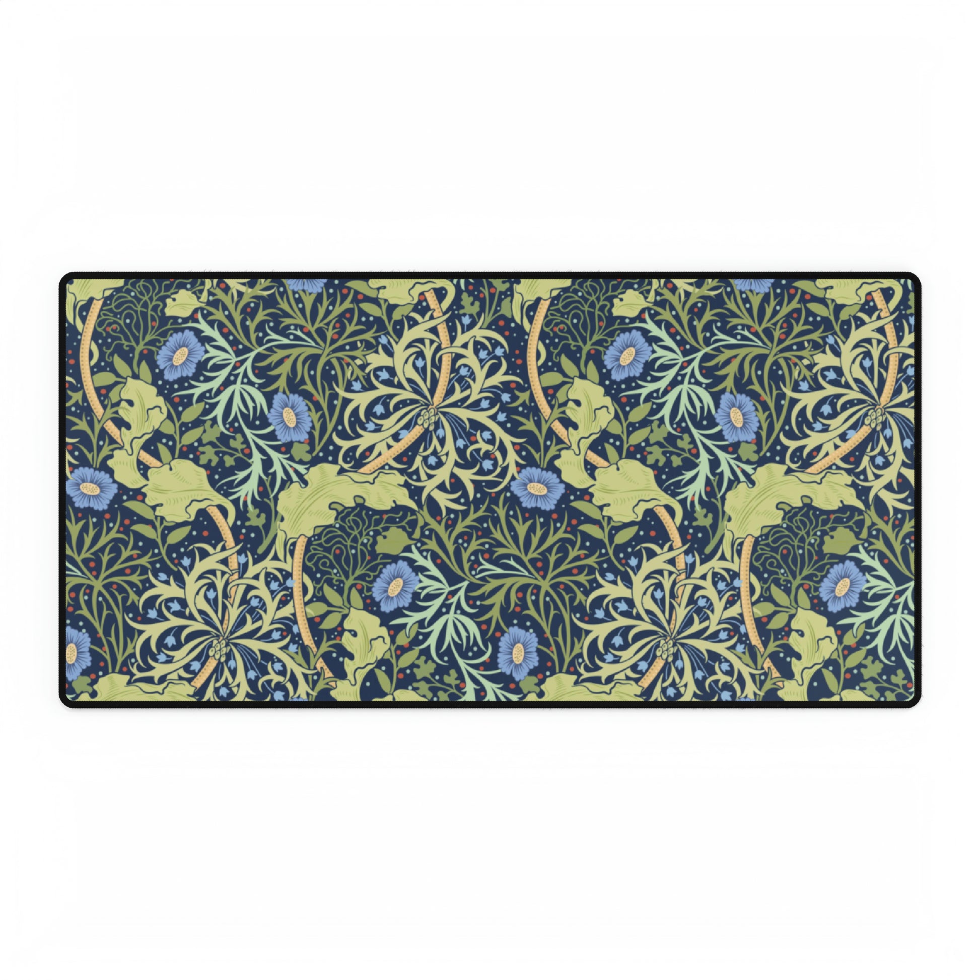 A large desk mat with a blue floral William Morris & Co pattern displayed under a monitor and accompanied by a keyboard and mouse.